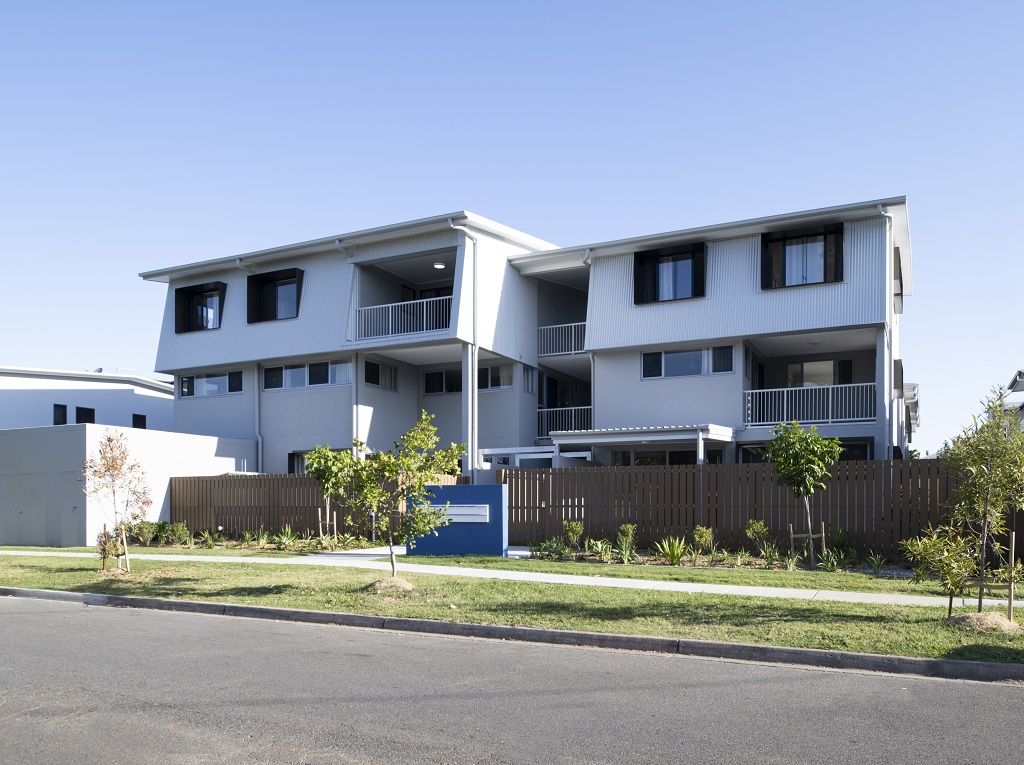 External view of the site, showing the steel cladding and render, with dark-coloured feature awnings. 