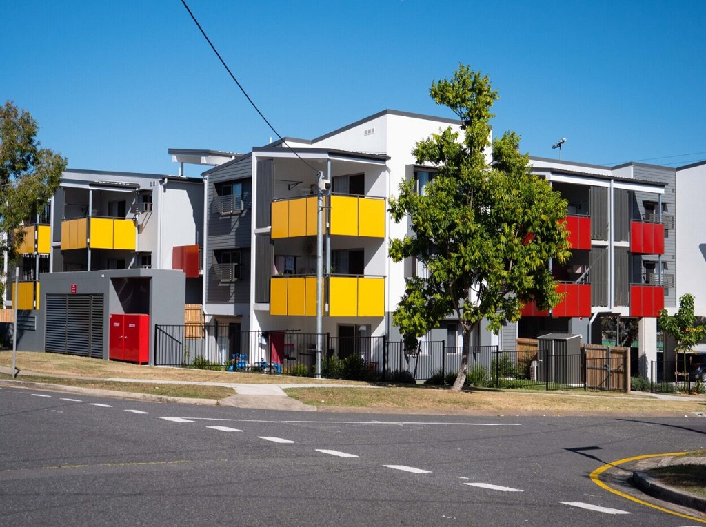 View of the building from the corner, showing bright feature balconies and screening. 