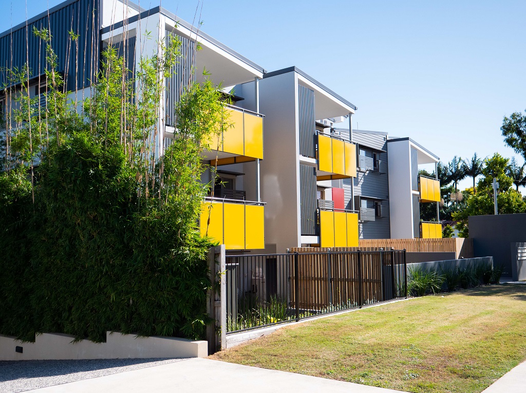 View from the driveway, showing balconies with bright yellow feature balconies, and screening.