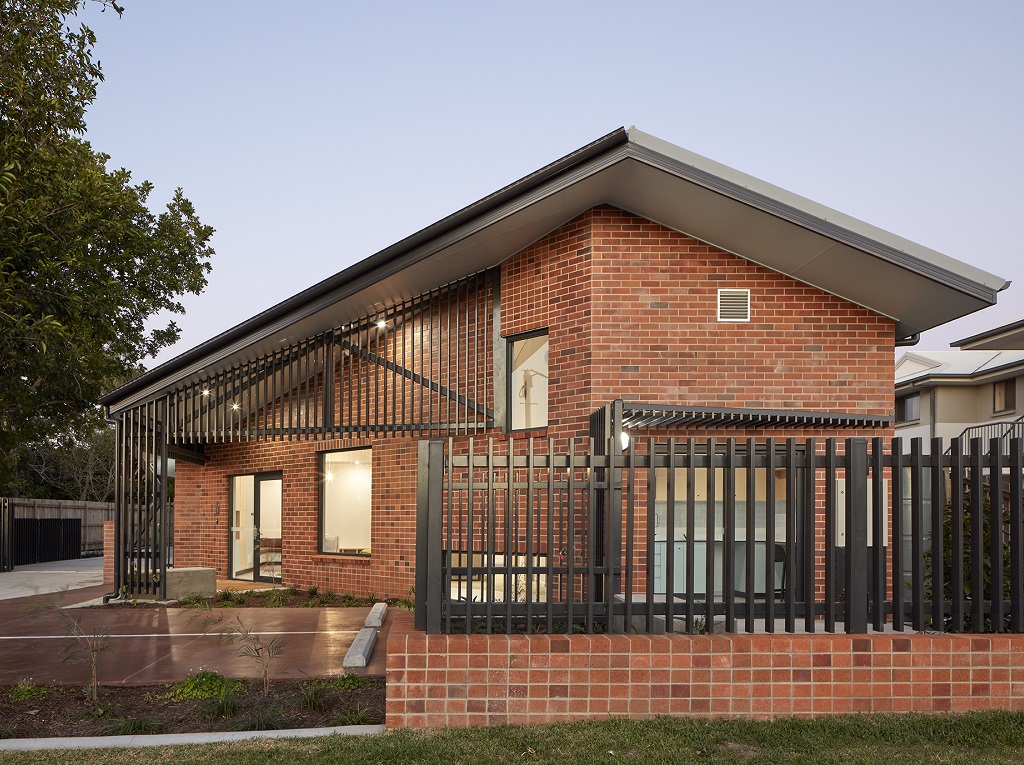 View from the street of the low-scale, red brick building, which has the appearance and scale of a house to fit in with the rest of the street. 